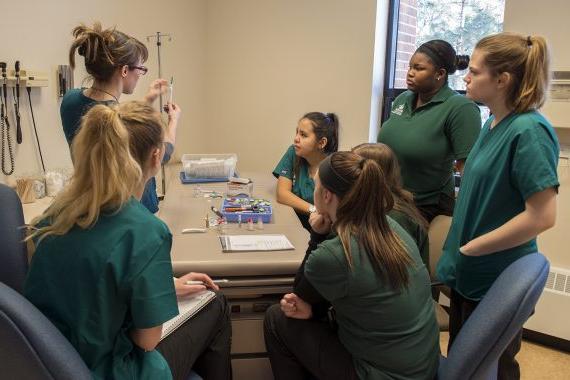 BSU nursing students talking around a table in the lab